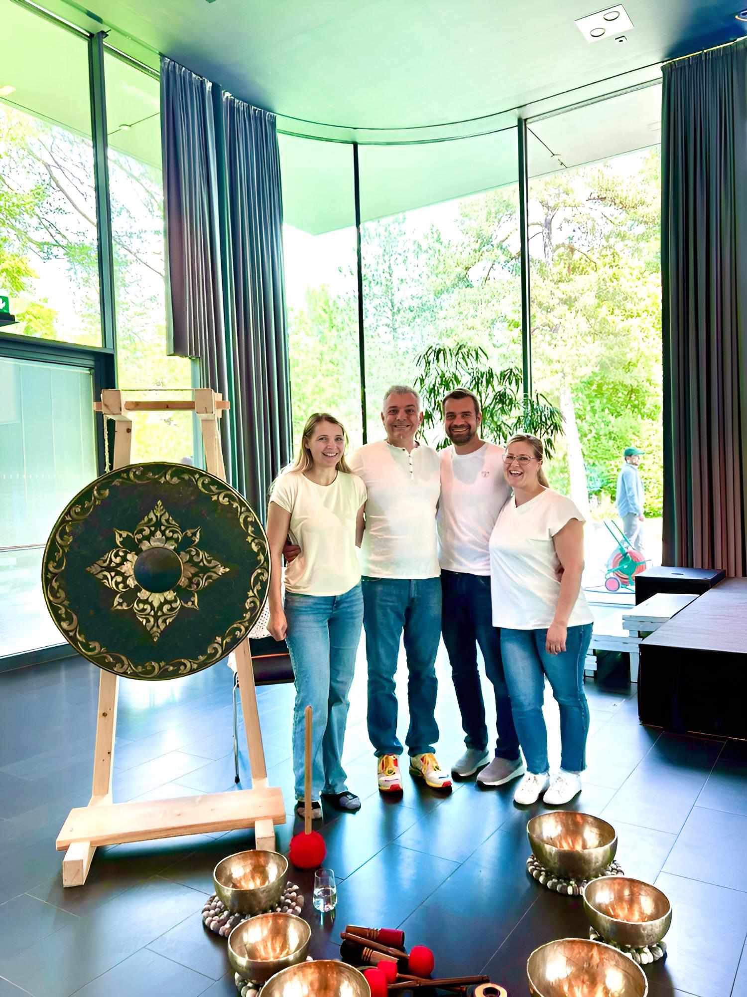 Gruppenfoto im Saal neben Gong und Klangschalen, Instrumente am Boden arrangiert.