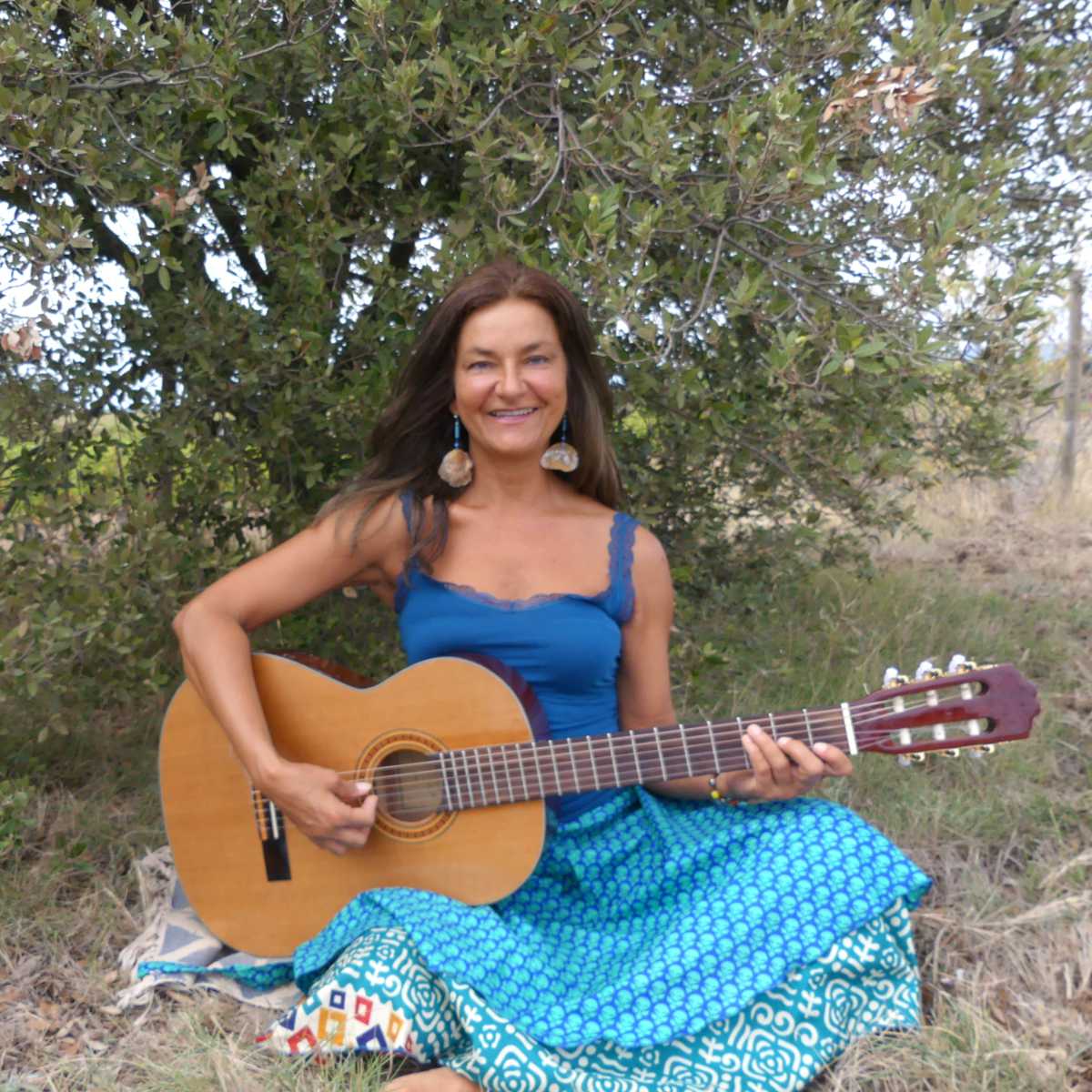 Patricia mit Gitarre in der Natur sitzend 